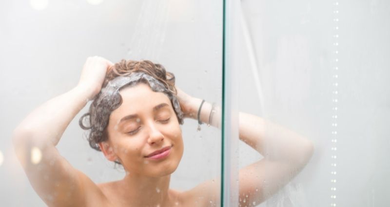 אישה במקלחת עם עיניים סגורות